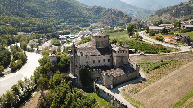 Aerial view of the historic Sarre Royal Castle with its stone fortifications and central tower overlooking the Dora Baltea river and lush alpine mountains Aosta Valley Italy. Aerial view of the historic Sarre Royal Castle with its stone fortifications and central tower overlooking the Dora Baltea river and lush alpine mountains Aosta Valley Italy.