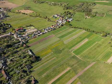 Aerial view of the village houses and narrow agricultural field strips surrounded by rolling green hills in Partizanska Lupca Zilina Region Slovakia.