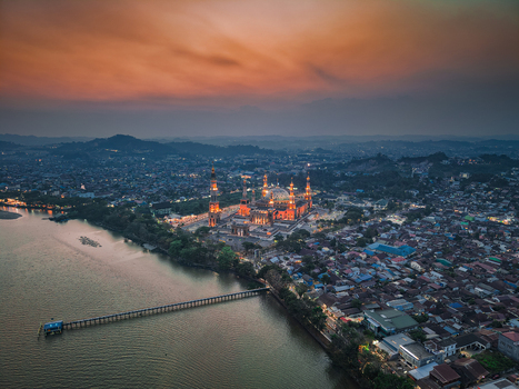 Aerial view of Baitul Muttaqien Mosque at the East Kalimantan Islamic Center illuminated at sunset by the Mahakam River in Samarinda East Kalimantan Indonesia.