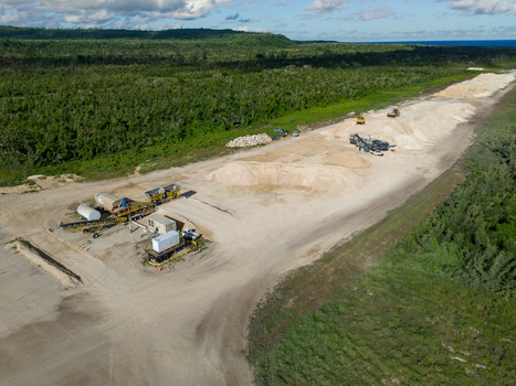 Aerial view of the restoration of North Field Base showing industrial equipment large sand piles and dirt roads in Northern Tinian Tinian Northern Mariana Islands.