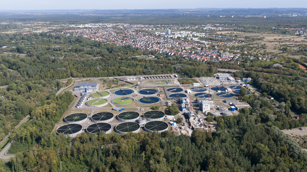 Aerial view of Klarwerk Karlsruhe featuring circular sedimentation tanks and industrial facilities surrounded by forest with the city in the background Karlsruhe Baden Wurttemberg Germany.