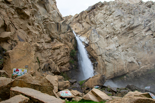 View of Khamosh Waterfall cascading down a rugged cliff face with large boulders in the foreground in Skardu Gilgit Pakistan.
