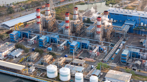 Aerial view of an industrial power plant with tall chimneys emitting smoke complex piping blue buildings and large storage tanks in Semarang Central Java Indonesia. Aerial view of an industrial power plant with tall chimneys emitting smoke complex piping blue buildings and large storage tanks in Semarang Central Java Indonesia.