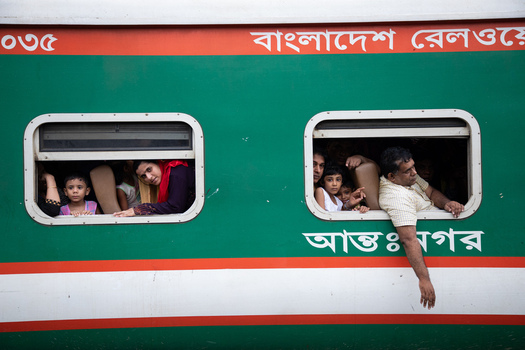 Dhaka Bangladesh 15 June 2018 View of passengers looking out of the windows of a green and red train carriage at Airport Railway Station. Dhaka Bangladesh 15 June 2018 View of passengers looking out of the windows of a green and red train carriage at Airport Railway Station.