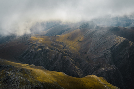 View of rugged mountain slopes with rocky textures and patches of golden grass partially obscured by low hanging clouds in Sierra de La Ventana Buenos Aires Province Argentina. View of rugged mountain slopes with rocky textures and patches of golden grass partially obscured by low hanging clouds in Sierra de La Ventana Buenos Aires Province Argentina.