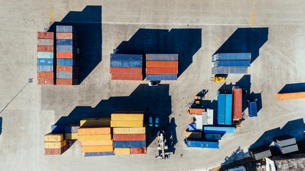 Aerial view of colorful shipping containers stacked in a logistics yard with long shadows cast on the concrete ground in Indjija Vojvodina Serbia.