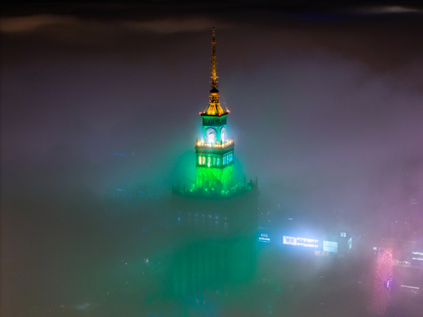 Aerial view of the illuminated Palace of Culture and Science shrouded in thick night fog with green and blue lights in Warsaw Poland. Aerial view of the illuminated Palace of Culture and Science shrouded in thick night fog with green and blue lights in Warsaw Poland.
