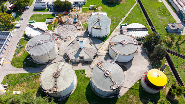 Aerial view of a water treatment plant featuring large circular sedimentation tanks a central hexagonal building and surrounding green lawns in an industrial site Milan Lombardy Italy. Aerial view of a water treatment plant featuring large circular sedimentation tanks a central hexagonal building and surrounding green lawns in an industrial site Milan Lombardy Italy.