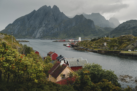 Sund Norway 04 September 2025 View of the coastal village of Sund nestled among dramatic mountains and rocky terrain with traditional red wooden houses along the fjord.