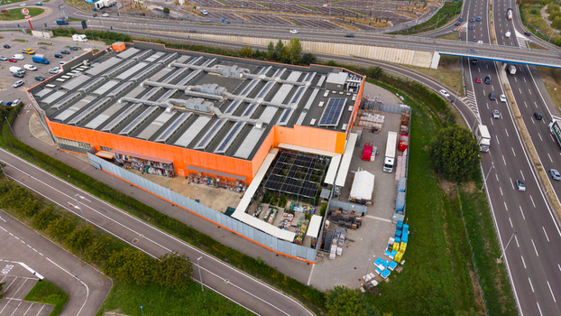 Aerial view of the OBI home improvement store with a large orange facade rooftop solar panels and an adjacent garden center area near a highway in San Giuliano Milanese Lombardia Italy. Aerial view of the OBI home improvement store with a large orange facade rooftop solar panels and an adjacent garden center area near a highway in San Giuliano Milanese Lombardia Italy.