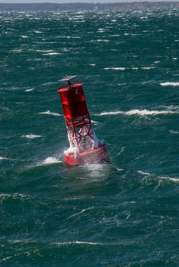 View of a red buoy covered in ice floating in the choppy green waters of Martha s Vineyard Edgartown Massachusetts United States.