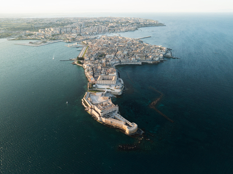 Aerial view of the Island of Ortigia featuring the Maniace Castle surrounded by the deep blue waters of the Ionian Sea in Syracuse Sicily Italy. Aerial view of the Island of Ortigia featuring the Maniace Castle surrounded by the deep blue waters of the Ionian Sea in Syracuse Sicily Italy.