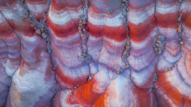Aerial view of the colorful striped badlands with layered sedimentary rock formations and scattered stones in Hanksville Utah United States.