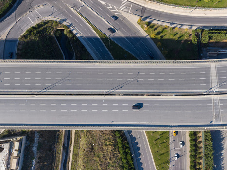 Aerial view of a multi lane highway interchange with vehicles driving on asphalt roads surrounded by green landscaping and long shadows in Istanbul Istanbul Turkiye.