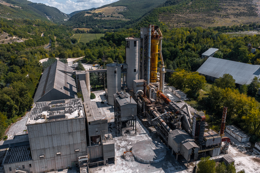 Aerial view of Sacci S.P.A. Centrale Cementerie Italiane cement factory with industrial silos processing machinery and surrounding green hills in Castelraimondo Marche Italy. Aerial view of Sacci S.P.A. Centrale Cementerie Italiane cement factory with industrial silos processing machinery and surrounding green hills in Castelraimondo Marche Italy.