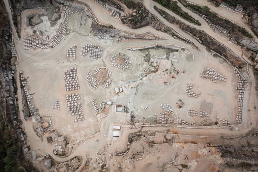 Aerial view of Cantera Porrino a large granite quarry with organized stone blocks winding access roads and industrial excavation patterns in O Porrino Pontevedra Spain. Aerial view of Cantera Porrino a large granite quarry with organized stone blocks winding access roads and industrial excavation patterns in O Porrino Pontevedra Spain.