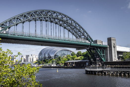 View of the Tyne Bridge and the Sage Gateshead building along the river in Newcastle upon Tyne England United Kingdom. View of the Tyne Bridge and the Sage Gateshead building along the river in Newcastle upon Tyne England United Kingdom.