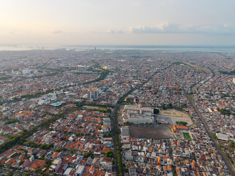 Surabaya Indonesia 28 August 2026 Aerial view of the dense urban cityscape of Surabaya with residential rooftops commercial buildings and roads stretching towards the horizon.