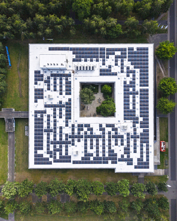 Aerial view of HTC 33 Design building featuring a large rooftop solar panel array and a central courtyard with trees in Eindhoven Noord Brabant Netherlands. Aerial view of HTC 33 Design building featuring a large rooftop solar panel array and a central courtyard with trees in Eindhoven Noord Brabant Netherlands.