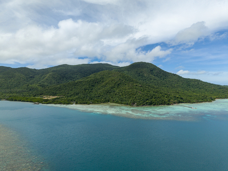 Aerial view of lush green island meets the turquoise sea under a sky dappled with soft white clouds Turtle Conservation Karimunjawa Central Java Indonesia.