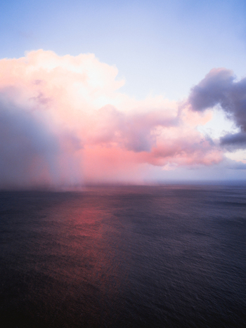 Aerial view of a serene seascape where the ocean meets the sky under a blanket of clouds painted with hues of pink and purple Reinebringen Nordland Norway.