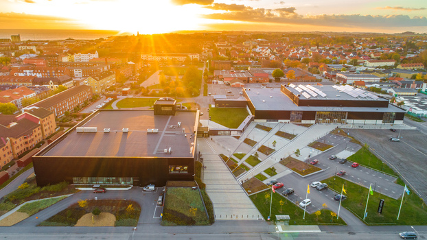 Aerial view of Ystad Arena featuring modern black buildings landscaped walkways and parking areas surrounded by the urban landscape at sunset Ystad Sweden. Aerial view of Ystad Arena featuring modern black buildings landscaped walkways and parking areas surrounded by the urban landscape at sunset Ystad Sweden.