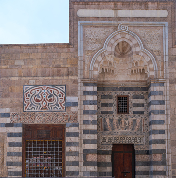 View of the intricate stone carvings and ablaq masonry on the facade of the Zawya and Sabil of Sultan Faraj Ibn Barquq in Cairo Egypt. View of the intricate stone carvings and ablaq masonry on the facade of the Zawya and Sabil of Sultan Faraj Ibn Barquq in Cairo Egypt.