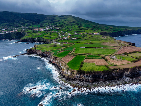 Aerial view of verdant fields meet the rugged coastline waves crashing against the rocks a vibrant tapestry of nature s artistry Flores A&ccedil;ores Portugal.
