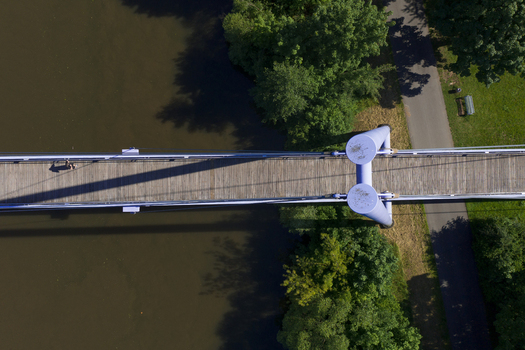 Aerial view of the Lila Brucke spanning over the water with lush green trees and a walking path on the bank in Forchheim Bavaria Germany. Aerial view of the Lila Brucke spanning over the water with lush green trees and a walking path on the bank in Forchheim Bavaria Germany.