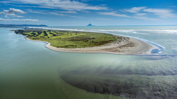 Aerial view of Ohope Spit with its sandy beach green coastal vegetation and clear turquoise waters under a bright blue sky in Ohope Bay of Plenty Region New Zealand.