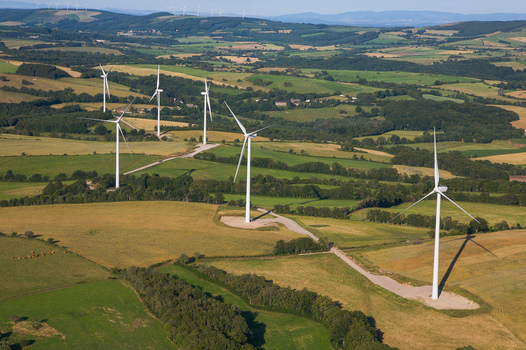 Aerial view of wind turbines standing tall against the rolling green fields and patchwork farmland Salles Curan Occitanie France. Aerial view of wind turbines standing tall against the rolling green fields and patchwork farmland Salles Curan Occitanie France.