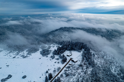 Aerial view of the snow covered Mummelsee lake surrounded by dense pine forests and winter mist in Seebach Baden Wurttemberg Germany. Aerial view of the snow covered Mummelsee lake surrounded by dense pine forests and winter mist in Seebach Baden Wurttemberg Germany.