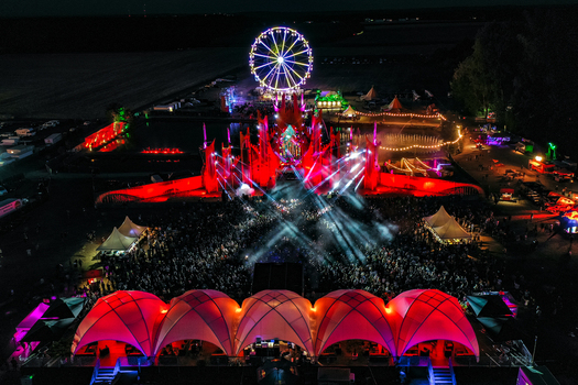 Herzogenaurach Germany 22 July 2022 Aerial view of the Open Beatz Festival at night featuring a large illuminated Ferris wheel main stage lights and a massive crowd of people. Herzogenaurach Germany 22 July 2022 Aerial view of the Open Beatz Festival at night featuring a large illuminated Ferris wheel main stage lights and a massive crowd of people.