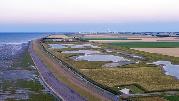 Aerial view of a gas transmission facility and the Eemshaven industrial area and wind farm with illuminated facilities along the coast in Eemshaven Groningen Netherlands at dusk Aerial view of a gas transmission facility and the Eemshaven industrial area and wind farm with illuminated facilities along the coast in Eemshaven Groningen Netherlands at dusk