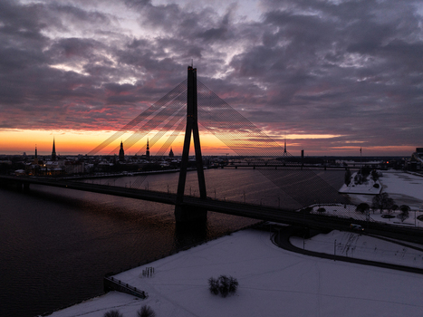Aerial view of the cable stayed Vansu Bridge spanning the Daugava River at sunset with the historic skyline of Riga in the background under a dramatic cloudy sky Riga Latvia. Aerial view of the cable stayed Vansu Bridge spanning the Daugava River at sunset with the historic skyline of Riga in the background under a dramatic cloudy sky Riga Latvia.