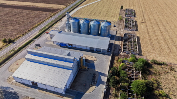 Aerial view of the storage silo facility with large metal grain bins industrial warehouses and adjacent agricultural fields in Bavaniste Vojvodina Serbia.