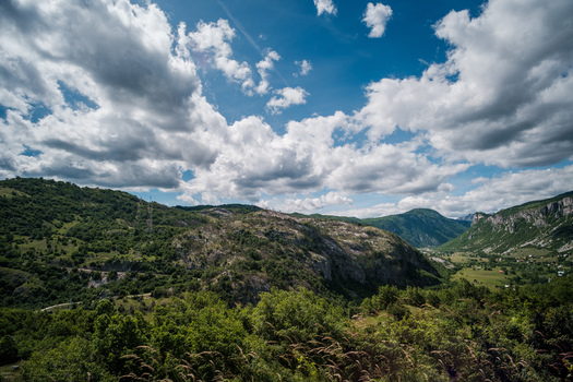 View of the rugged mountainous landscape surrounding the town of Savnik with lush green hills rocky outcrops and a dramatic cloudy sky in Savnik Savnik Municipality Montenegro.