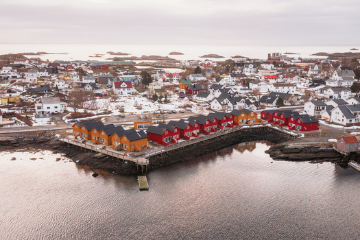 Aerial view of colorful houses stand in contrast to the grey landscape and calm waters Ballstad Nordland Norway. Aerial view of colorful houses stand in contrast to the grey landscape and calm waters Ballstad Nordland Norway.