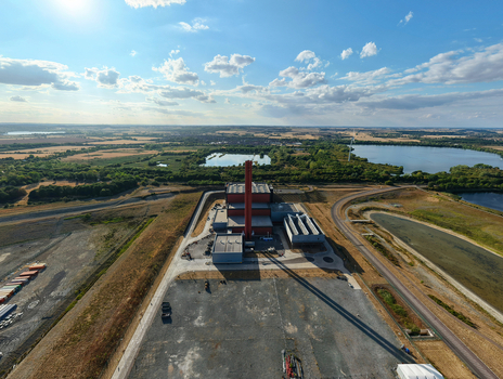 Aerial view of Rookery South ERF facility with its tall chimney surrounded by industrial grounds nearby lakes and green landscape in Stewartby England United Kingdom. Aerial view of Rookery South ERF facility with its tall chimney surrounded by industrial grounds nearby lakes and green landscape in Stewartby England United Kingdom.