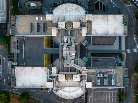 Aerial view of a modern datacenter complex featuring rooftop HVAC units technical infrastructure and surrounding parking areas in Settecamini Lazio Italy.