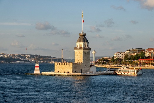 View of the historic Maiden s Tower surrounded by the waters of the Bosphorus with a ferry docked nearby and the Bosphorus Bridge in the distance in Uskudar Istanbul Turkey. View of the historic Maiden s Tower surrounded by the waters of the Bosphorus with a ferry docked nearby and the Bosphorus Bridge in the distance in Uskudar Istanbul Turkey.
