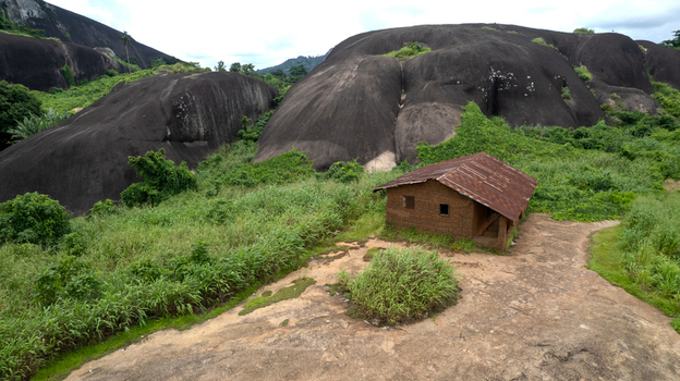 Aerial view of Idanre Hill with a small rustic house situated near large granite rock formations and green vegetation Idanre Ondo State Nigeria. Aerial view of Idanre Hill with a small rustic house situated near large granite rock formations and green vegetation Idanre Ondo State Nigeria.