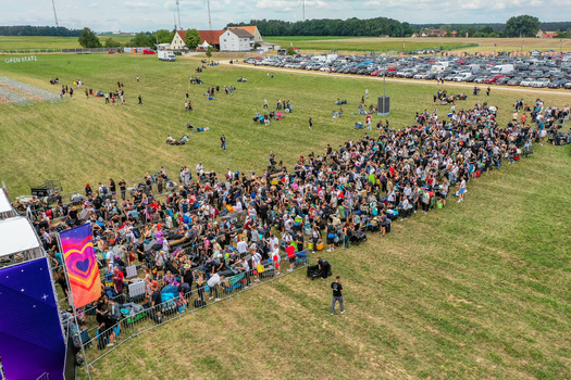 Herzogenaurach Germany 25 July 2025 Aerial view of the Open Beatz Festival entrance with a large crowd of people queuing on a green field next to a parking lot and rural buildings. Herzogenaurach Germany 25 July 2025 Aerial view of the Open Beatz Festival entrance with a large crowd of people queuing on a green field next to a parking lot and rural buildings.