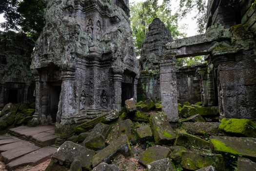 View of the ancient moss covered stone ruins of Ta Prohm temple with weathered carvings and scattered blocks in the jungle of Krong Siem Reap Siem Reap Province Cambodia. View of the ancient moss covered stone ruins of Ta Prohm temple with weathered carvings and scattered blocks in the jungle of Krong Siem Reap Siem Reap Province Cambodia.