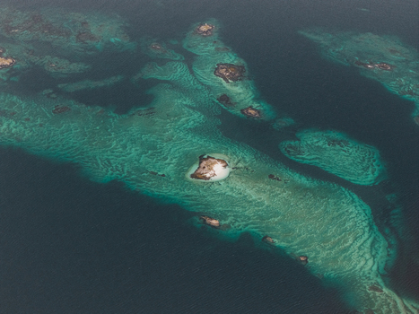 Aerial view of turquoise waters and rocky islets of the Senja archipelago with clear shallow reefs and deep blue sea in Senja Troms Norway.