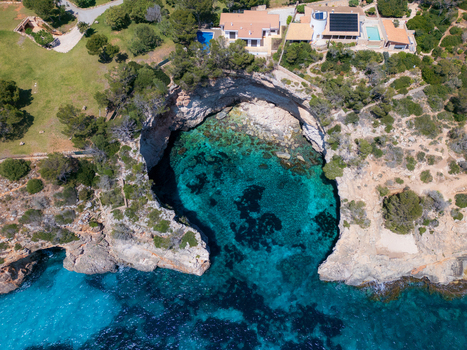 Aerial view of the turquoise waters of Cala Llombards cove surrounded by rocky cliffs and coastal villas Cala Llombards Illes Balears Spain. Aerial view of the turquoise waters of Cala Llombards cove surrounded by rocky cliffs and coastal villas Cala Llombards Illes Balears Spain.