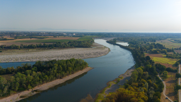Aerial view of the Po River with low water levels due to drought exposing sandy riverbeds and sediments surrounded by lush vegetation in Castelvetro Piacentino Emilia Romagna Italy. Aerial view of the Po River with low water levels due to drought exposing sandy riverbeds and sediments surrounded by lush vegetation in Castelvetro Piacentino Emilia Romagna Italy.