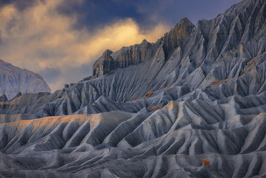 Aerial view of the dramatic eroded rock formations of the badlands at golden hour with sharp ridges and deep shadows in Hanksville Utah United States.