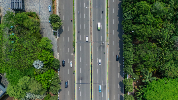 Aerial view of a multi lane highway with cars driving through lush green trees in Jakarta Indonesia. Aerial view of a multi lane highway with cars driving through lush green trees in Jakarta Indonesia.