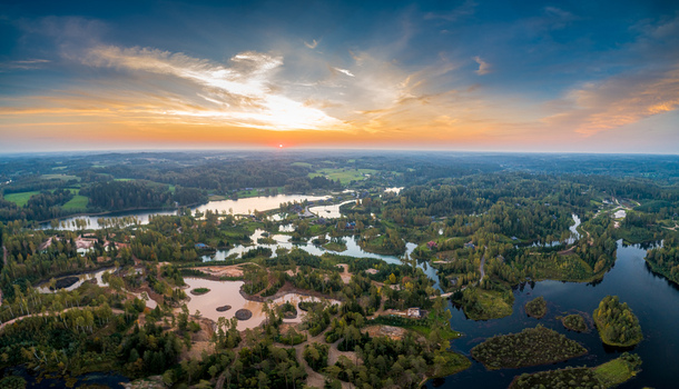 Aerial view of a serene landscape featuring interconnected lakes dense forests and winding waterways under a vibrant sunset sky in Latvia. Aerial view of a serene landscape featuring interconnected lakes dense forests and winding waterways under a vibrant sunset sky in Latvia.